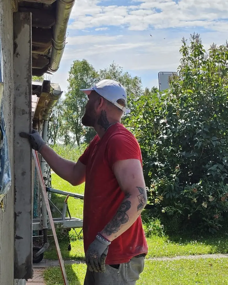 Julian Werning zieht frischen Putz an einer Hauswand mit der Richtlatte ab